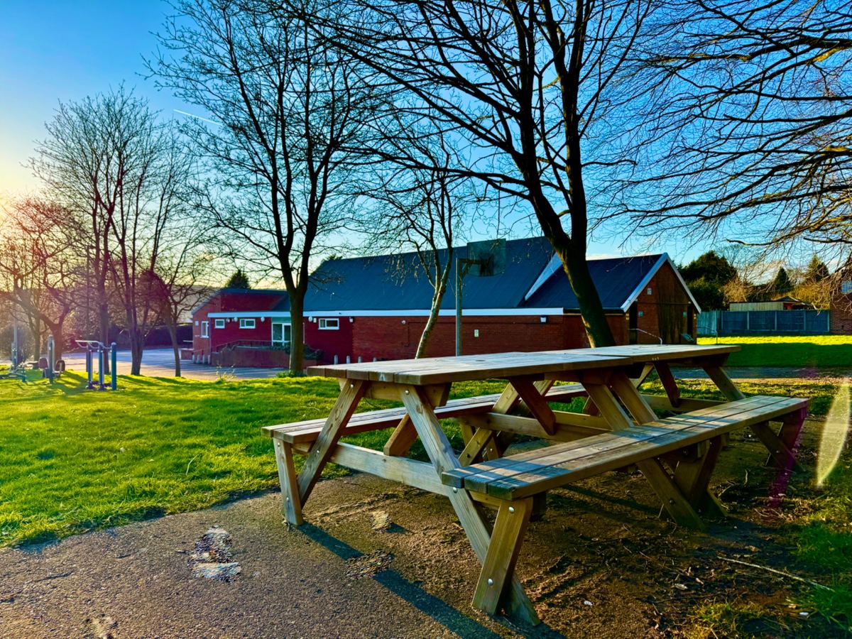 Whitmore Village Hall from the grounds, with a picnic bench and trees